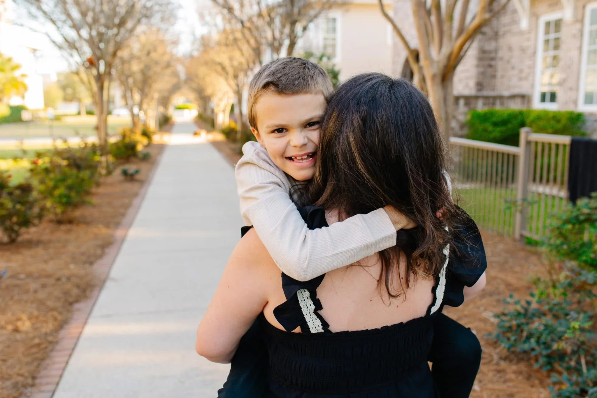 Jacob hugging Merrie on a tree-lined sidewalk at golden hour